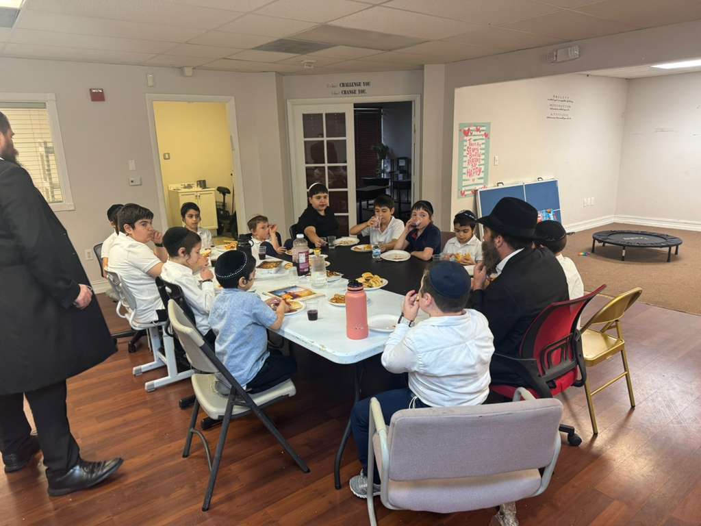 Talmidim around the table at a farbrengen with the Rebbi