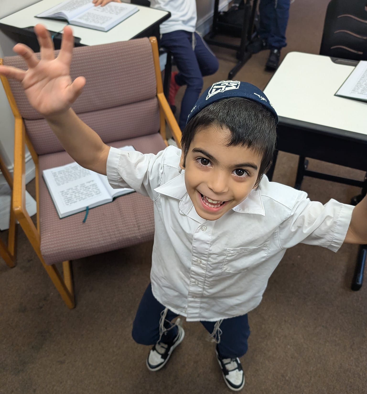Talmid joyfully raising his hands in the classroom